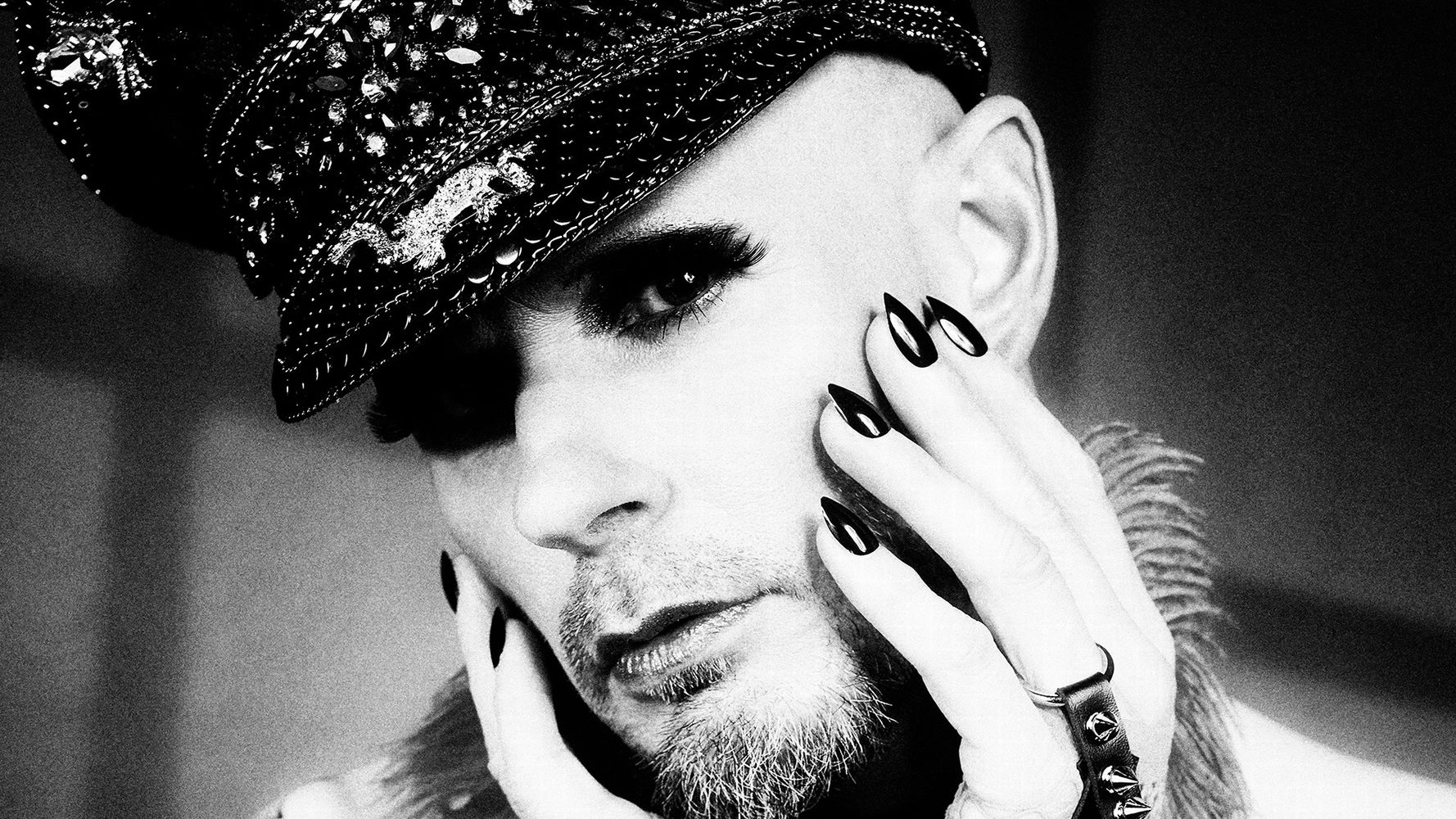 Androgynes Studiofoto in Schwarzweiß mit Netzstulpen, Glitzerhut und Stachelschmuck – Fetischfotografie Hell On Heels Photography Düsseldorf