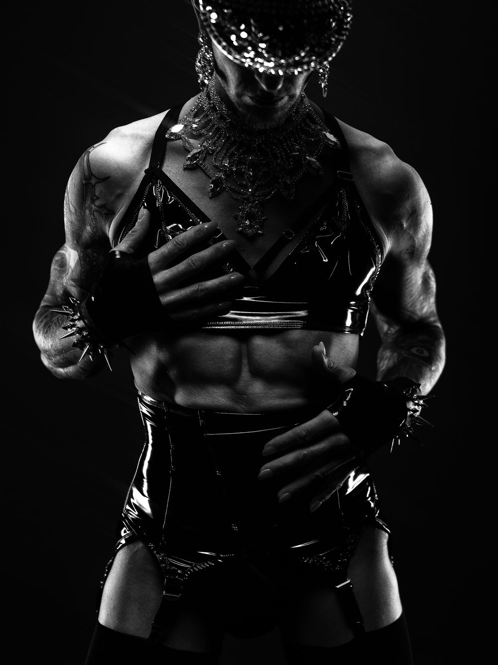 Sinnliches Low-Key-Fetischporträt eines maskulinen Models in Lack und Schmuck – Studiofotografie bei Hell On Heels in Düsseldorf und Köln