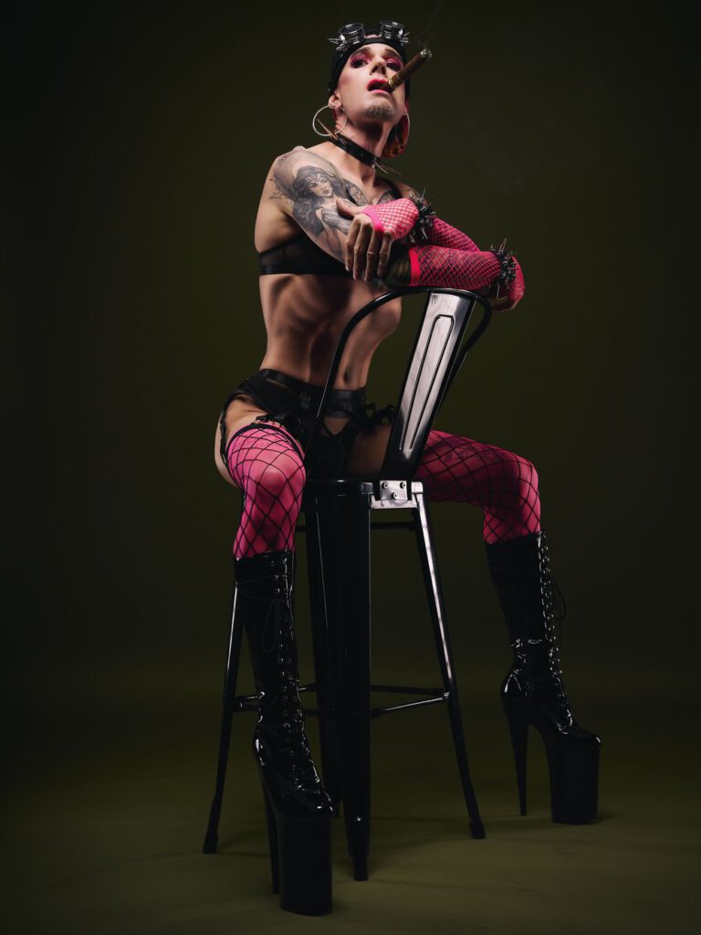 Stilisiertes Fetisch-Porträt in Netzstrümpfen und Plateaustiefeln mit Cigarre – Queer Fotografie von Hell On Heels aus Düsseldorf